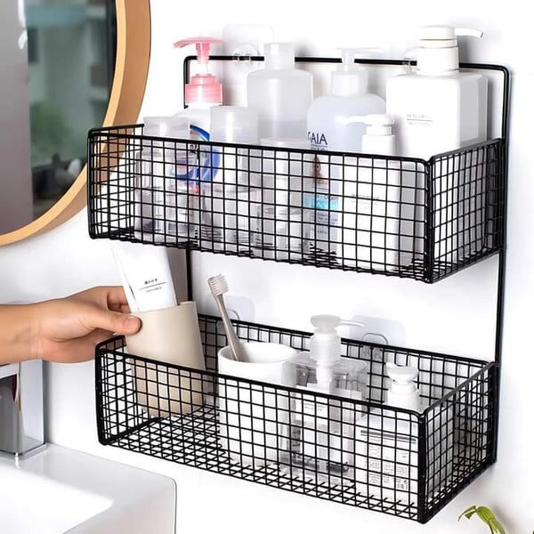 Black wire wall-mounted storage baskets with toiletries on a white wall.