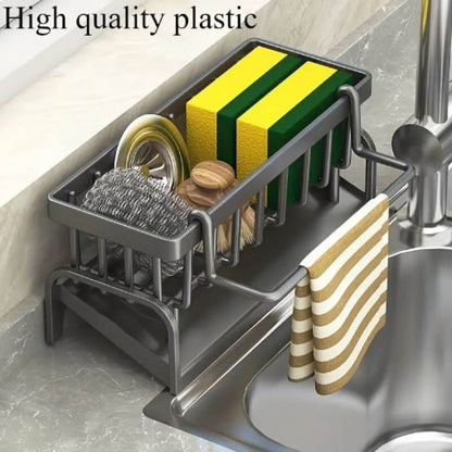 Kitchen sink caddy with sponges, scrubber, and towel on a kitchen counter.