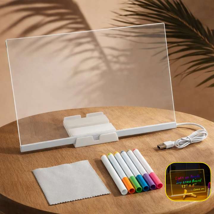 Clear electronic display board with markers and cleaning cloth on a wooden surface