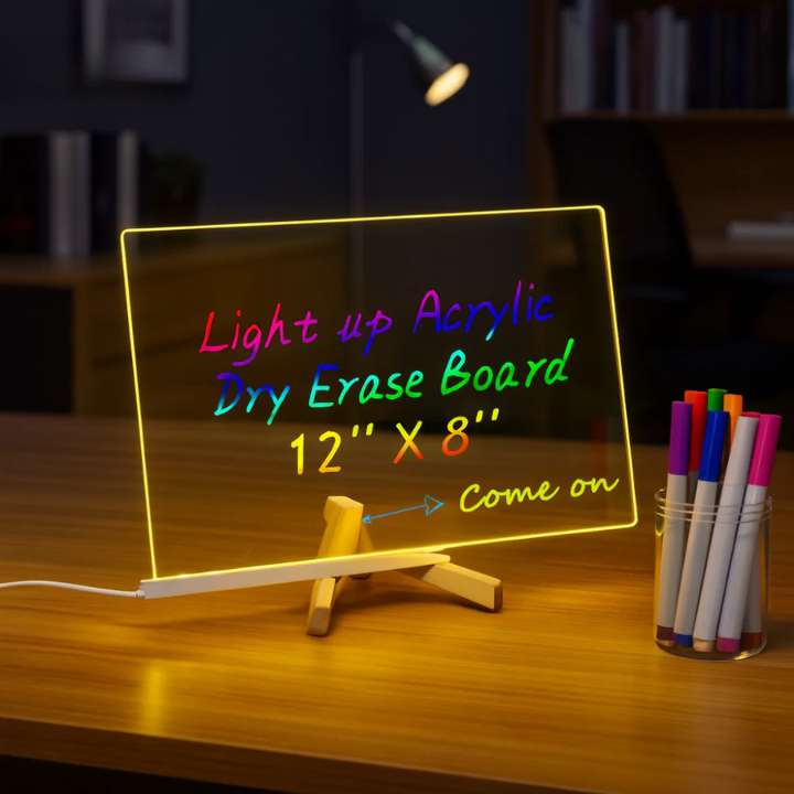 Light-up acrylic dry erase board with colorful markers on a wooden surface