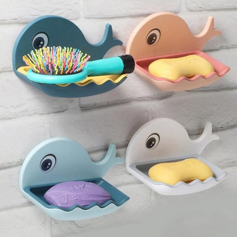 Set of four whale-shaped soap holders with colorful soaps on a light wooden background