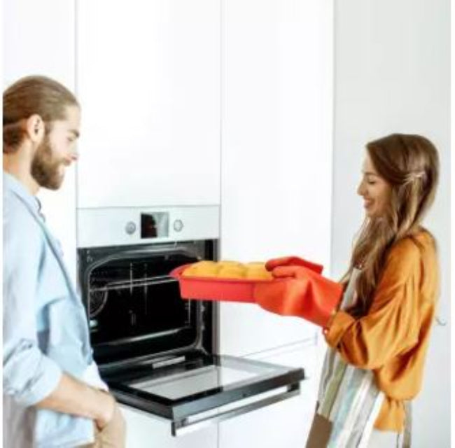 Flexible non-stick silicone loaf pan in red, shown holding a baked banana bread loaf that is easily being removed from the mold, illustrating the easy release.