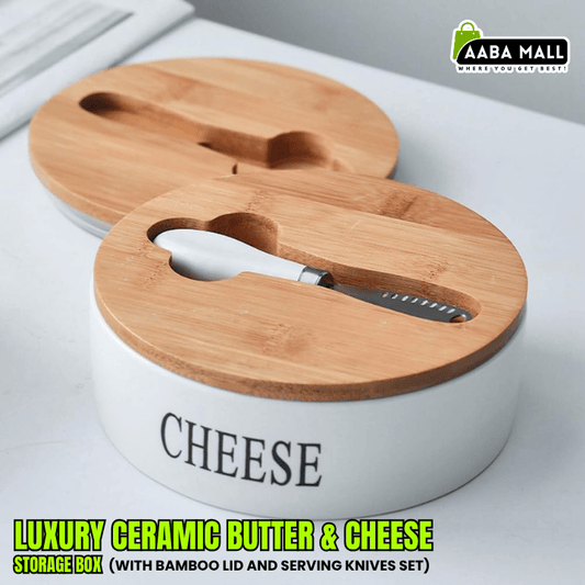 Elegant white ceramic cheese and butter storage box with a natural bamboo lid and three stainless steel serving knives displayed next to it on a wooden counter.
