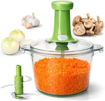Green manual vegetable chopper with a clear container filled with shredded carrots, surrounded by vegetables on a white background.