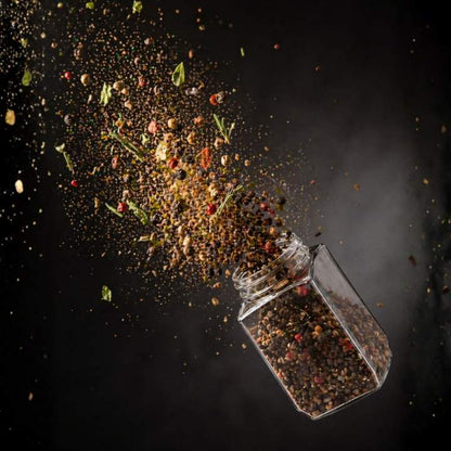 Spices spilling out of a glass container on a dark background