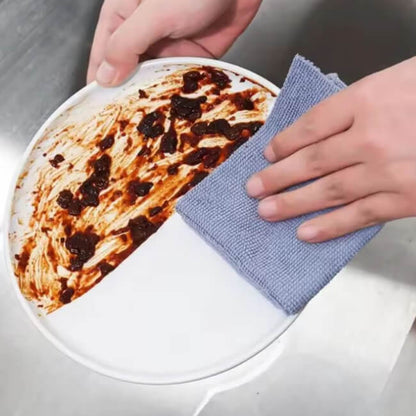 Person cleaning a plate with a blue microfiber cloth