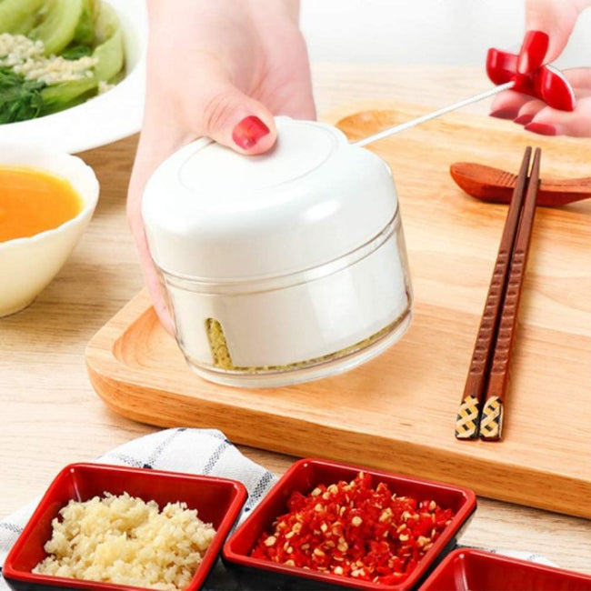 Mini hand manual food chopper and mincer with pull-cord mechanism, showing chopped garlic inside the portable vegetable dicer