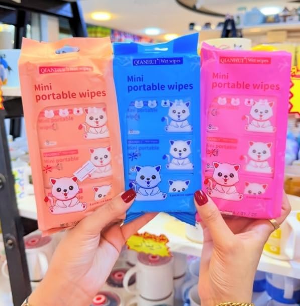 Three packages of mini portable wipes held by a person in a store setting.