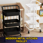 Modern minimalist black metal kitchen trolley with wooden handle, on wheels, holding kitchen accessories and utensils.