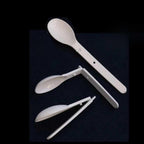 Set of white plastic utensils including a spoon, fork, and chopsticks on a black background