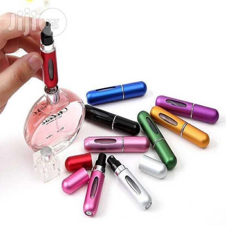 Colorful perfume atomizers scattered around a clear perfume bottle on a white background