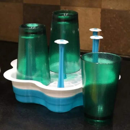 Green plastic cups with blue straws in a white holder on a dark surface.