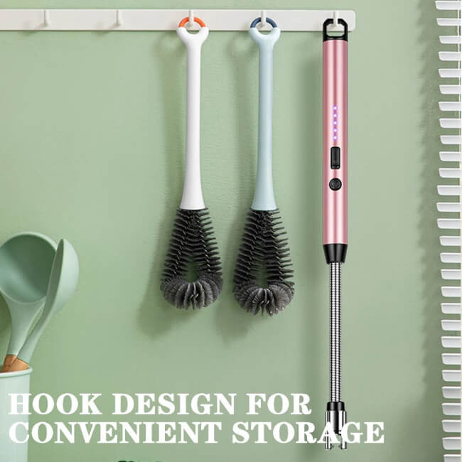 Three cleaning brushes with a pink extendable handle hanging on a hook against a green wall.
