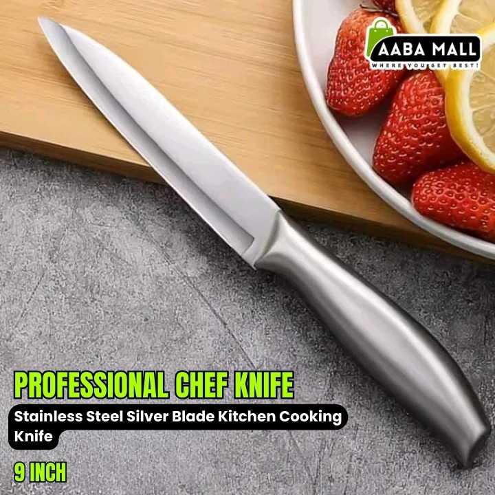 Professional chef knife with a stainless steel blade on a gray surface, next to a bowl of strawberries and lemon slices.