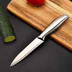 Knife on a wooden cutting board with vegetables on a dark surface
