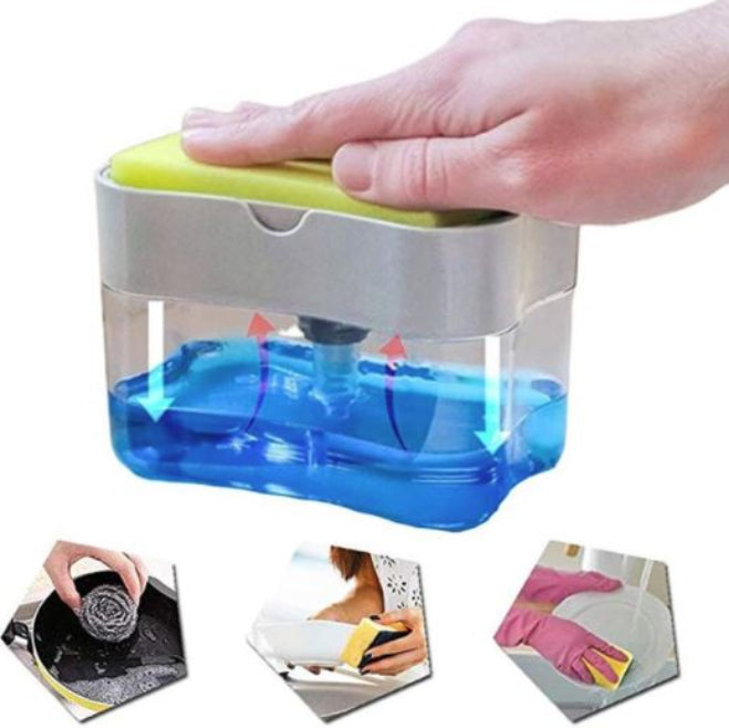 A white plastic push soap dispenser with a clear reservoir, showing a yellow scrub sponge resting on top of the pump mechanism, positioned next to a kitchen sink.