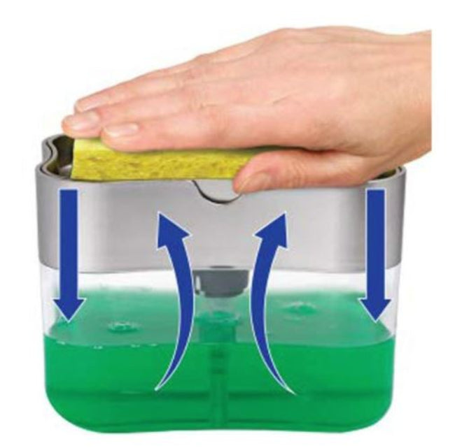 A white plastic push soap dispenser with a clear reservoir, showing a yellow scrub sponge resting on top of the pump mechanism, positioned next to a kitchen sink.