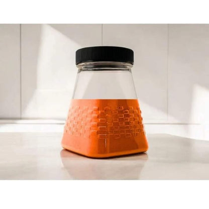 Clear container with orange base and black lid on a white surface