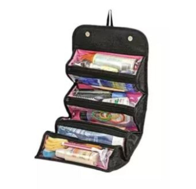 Luxury Roll-N-Go cosmetic bag in a black or neutral color, shown unrolled and hanging, displaying the four clear, zippered compartments filled with various makeup items and travel toiletries.