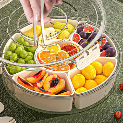 Close-up of a white multi-compartment rotating snack organizer tray with a lid, open and filled with colorful candies, nuts, and dried fruit.
