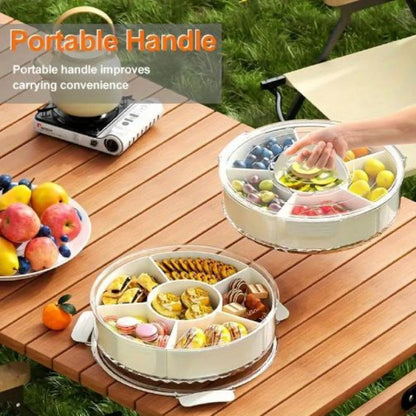 Close-up of a white multi-compartment rotating snack organizer tray with a lid, open and filled with colorful candies, nuts, and dried fruit.