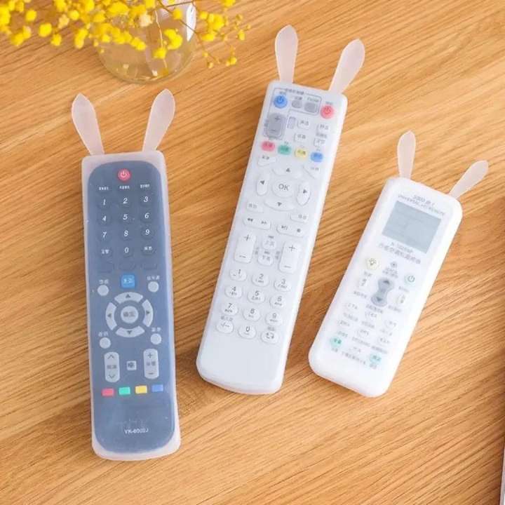 Three remote control covers with rabbit ears on a wooden surface.