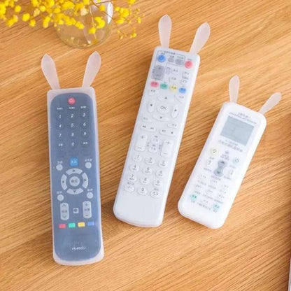 Three remote control covers with rabbit ears on a wooden surface.