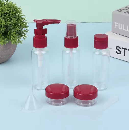 Clear bottles with red caps on a light blue surface with a plant and box in the background.