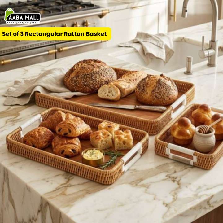 Set of 3 rectangular rattan baskets on a kitchen counter with bread and pastries.