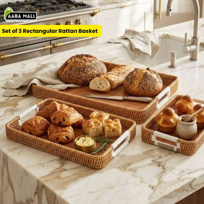 Set of 3 rectangular rattan baskets on a kitchen counter with bread and pastries.