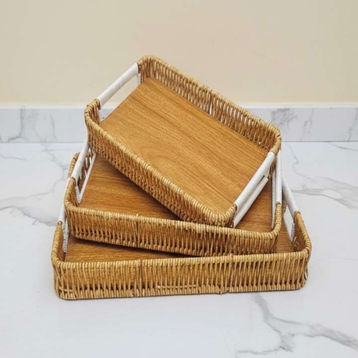Set of three woven trays with white handles on a marble surface