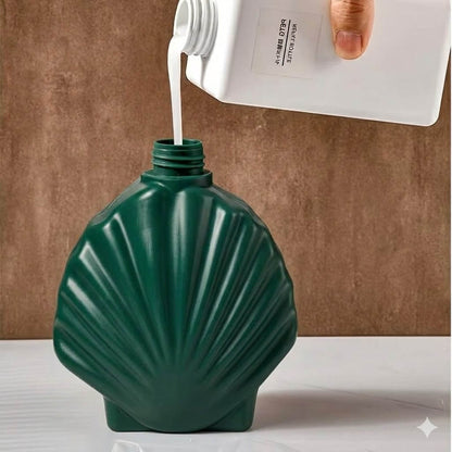 Green shell-shaped bottle being filled with a white liquid from a white container.