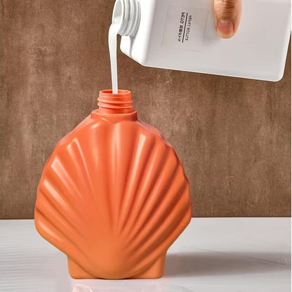 Orange shell-shaped bottle being filled with a white liquid from a white container.