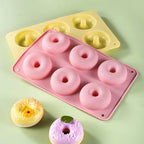 Pink silicone donut mold with pink donuts on a green background