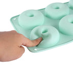 Silicone donut mold with a hand pressing one of the donut shapes.