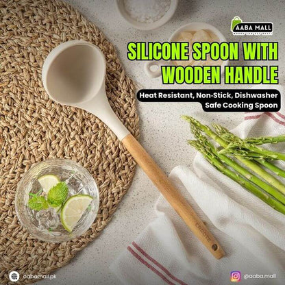 Silicone spoon with wooden handle on a woven mat with asparagus and a glass of water.