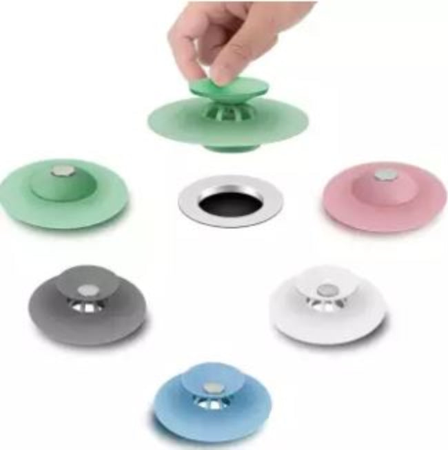 Silicone drain strainer hair catcher and water stopper in grey, shown placed in a bathtub drain in the filter mode, catching hair while water is running.