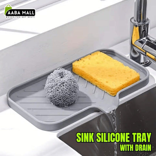 Sink silicone tray with drain holding a sponge and scrubber, placed over a running faucet.