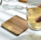 Wooden coaster on a white surface with a glass of liquid nearby