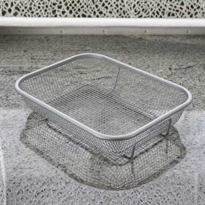 Metal wire laundry basket on a concrete surface with a white chair in the background