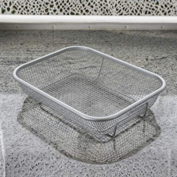 Metal wire laundry basket on a concrete surface with a white chair in the background
