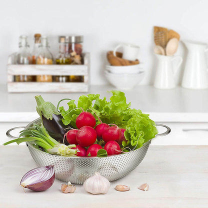 Colander with radishes, lettuce, and other vegetables on a kitchen counter.