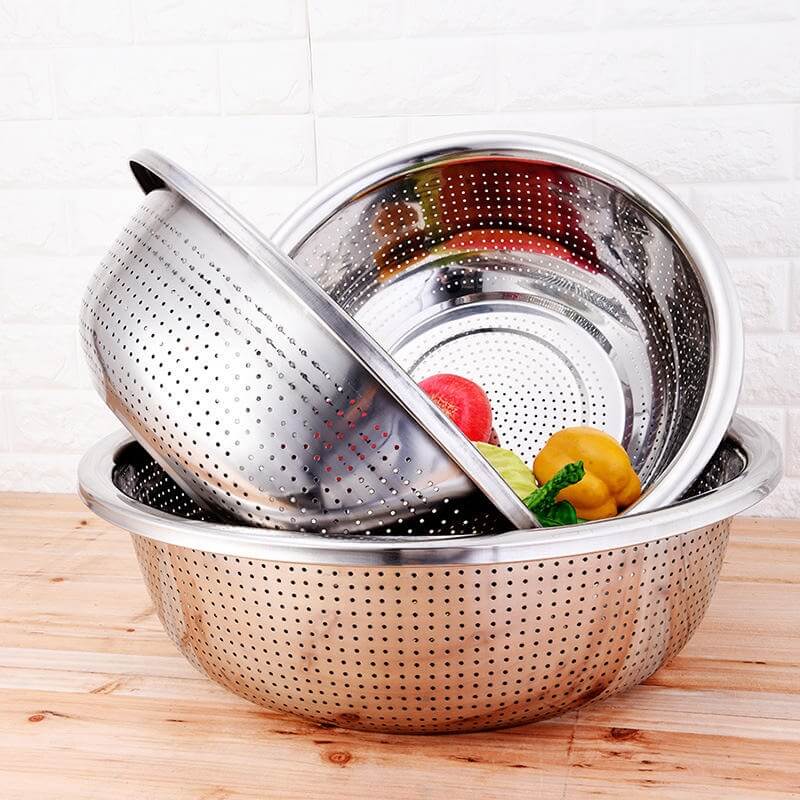Stainless steel colander with vegetables on a wooden surface