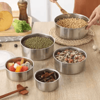 Set of stainless steel bowls containing various foods on a wooden table.