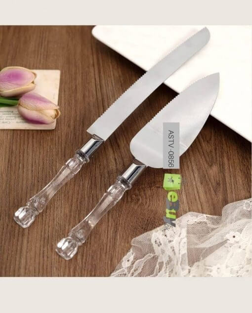 Decorative cake knife and server set on a wooden surface with a lace fabric at the bottom.