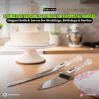 Stainless steel cake serving set with crystal handles on a wooden table with a cake in the background.