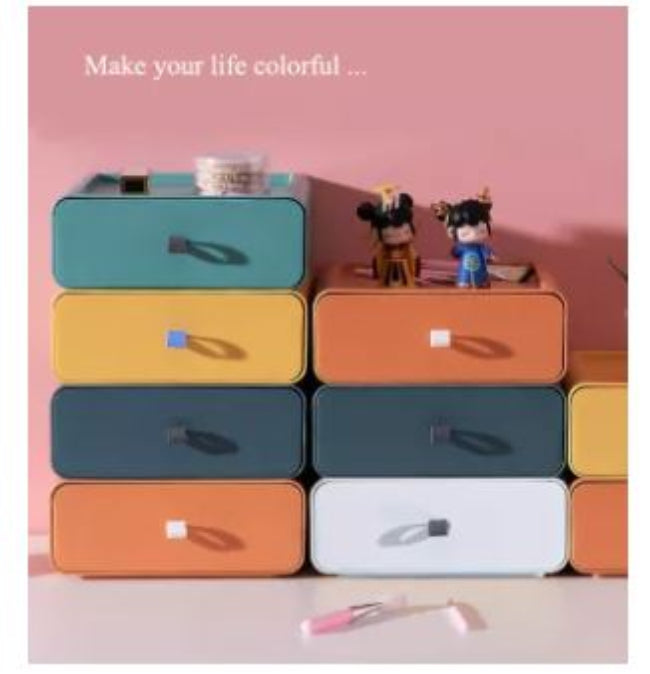 Set of clear stackable plastic drawer organizer boxes, one filled with makeup products and another with jewelry, shown neatly stored on a vanity desk.