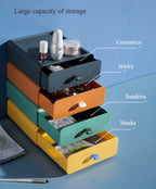 Set of clear stackable plastic drawer organizer boxes, one filled with makeup products and another with jewelry, shown neatly stored on a vanity desk.