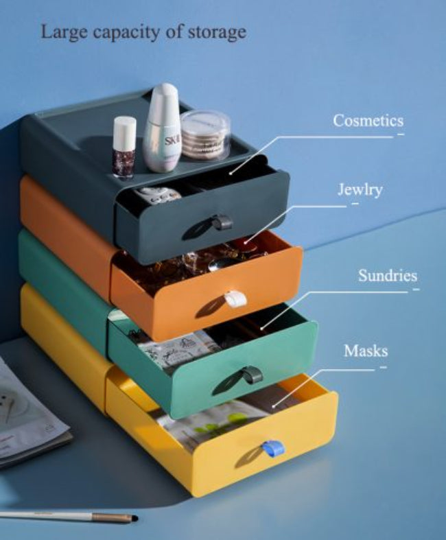 Set of clear stackable plastic drawer organizer boxes, one filled with makeup products and another with jewelry, shown neatly stored on a vanity desk.