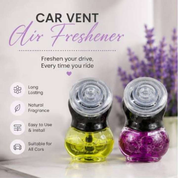 Two car air freshener vent devices shown on a light surface with promotional text on the left and blurred purple flowers in the background. The left device contains yellow liquid, and the right device contains purple glittery liquid.